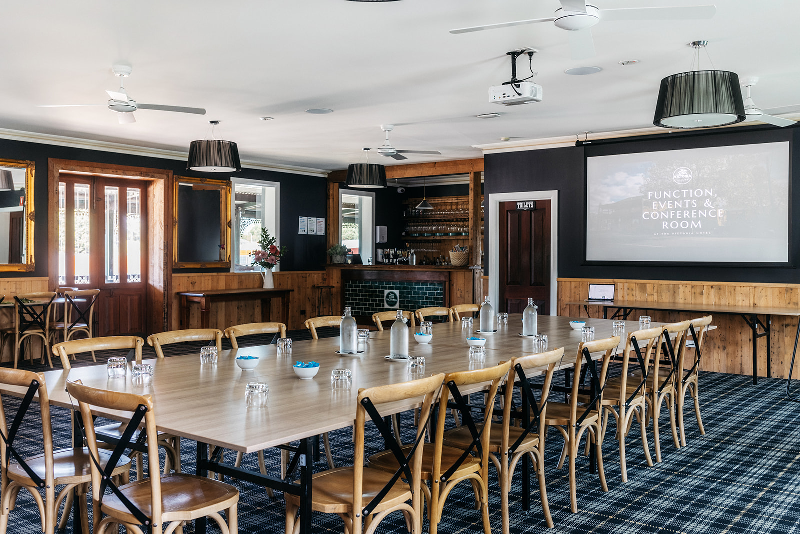 Conference room hire at The Victoria Hotel Woodend. Showing the bar within the room, projector screens, and elegant tables with elegant ambient